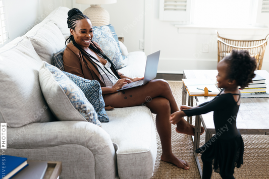 Black daughter interrupts mom working from home on laptop