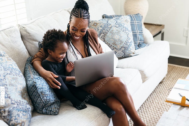 Black daughter interrupts mom working from home on laptop