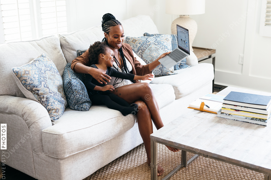 Black daughter interrupts mom working from home on laptop