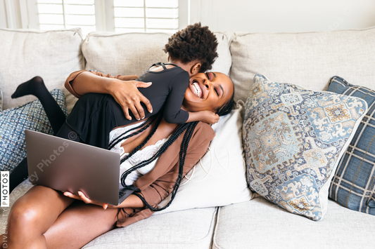Black daughter interrupts mom working from home on laptop