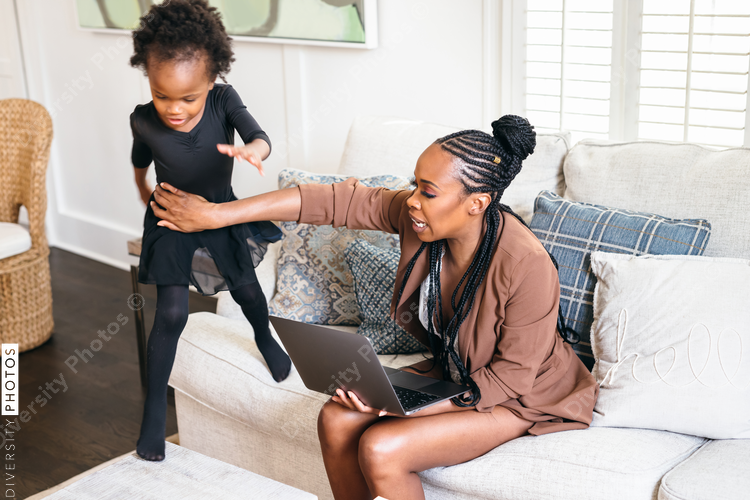 Black daughter interrupts mom working from home on laptop