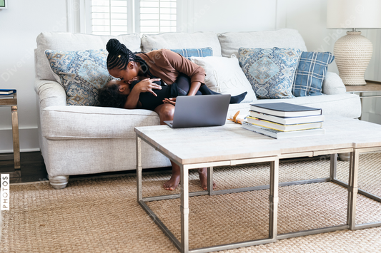 Black daughter interrupts mom working from home on laptop