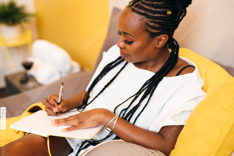 Black woman writes in journal at home in bed