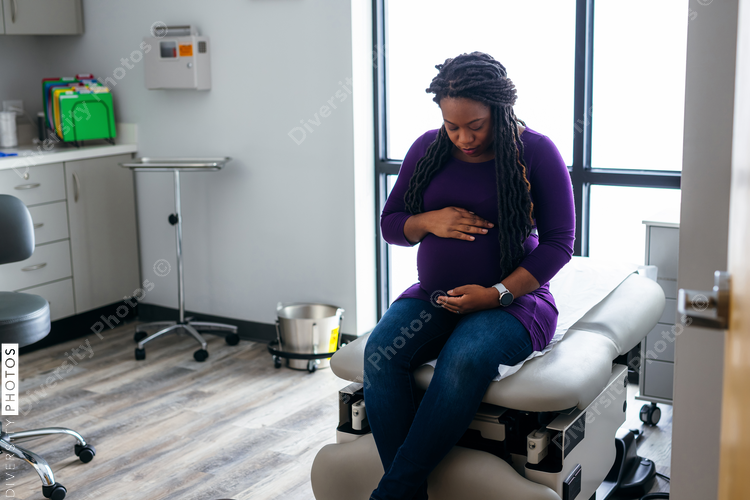 Black pregnant woman waiting in medical exam room at the Doctors office