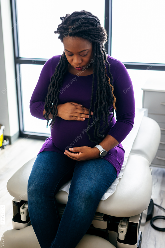Black pregnant woman waiting in medical exam room at the Doctors office