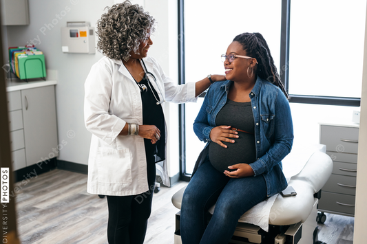 Black female doctor speaks with female pregnant patient