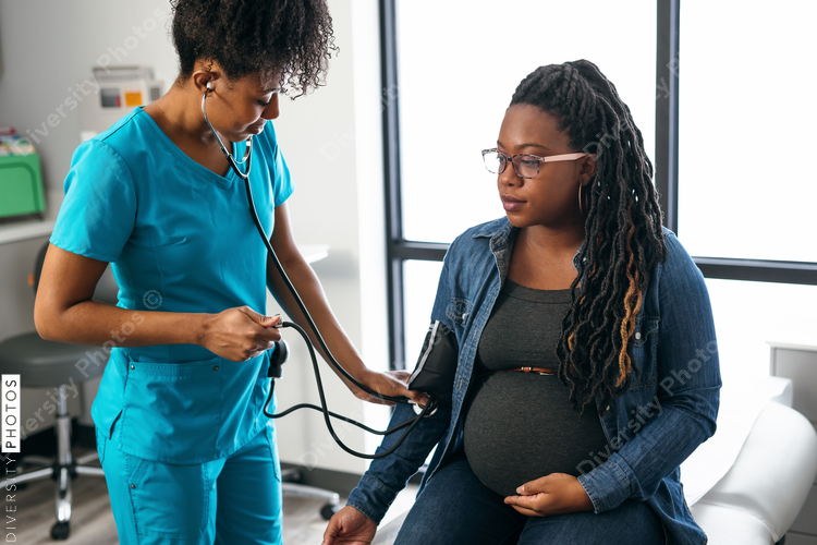 Black woman nurse checks vitals of pregnant patient