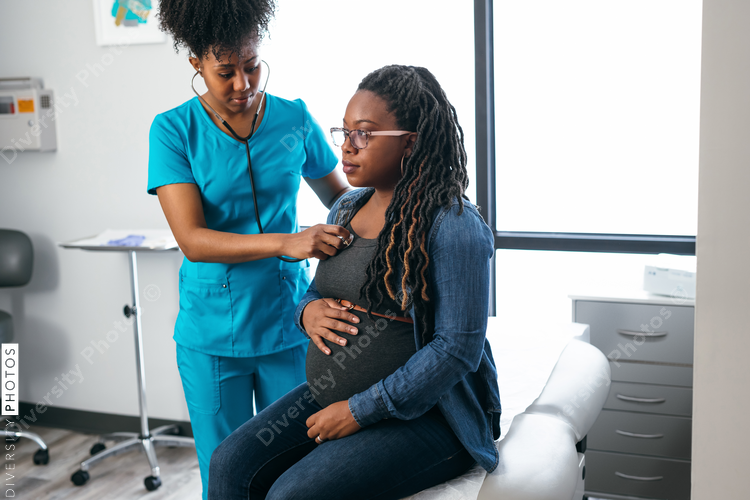 Black woman nurse checks vitals of pregnant patient