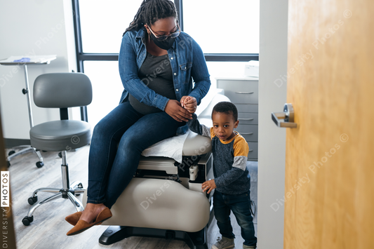Black mom and toddler waiting in medical exam room