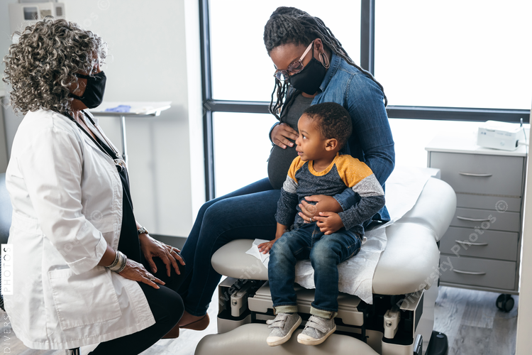 Female doctor speaking with patients, mother and toddler 