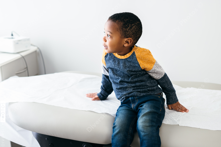 Black toddler boy waits in medical exam room