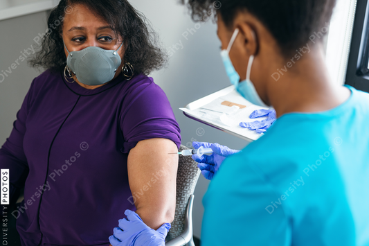 Black senior woman gets vaccine, from nurse at doctors office