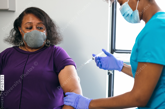 Black senior woman gets vaccine, from nurse at doctors office