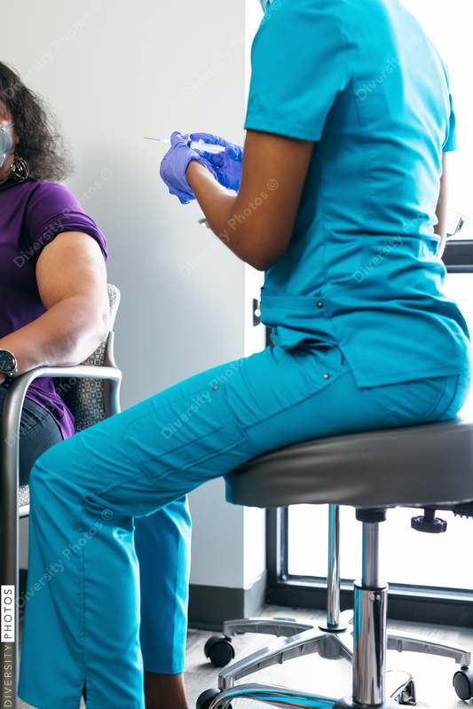 Black senior woman gets vaccine, from nurse at doctors office