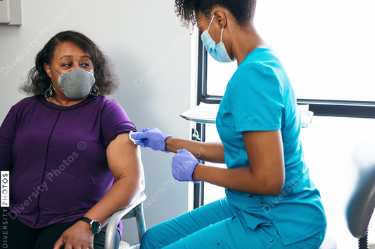 Black senior woman gets vaccine, from nurse at doctors office