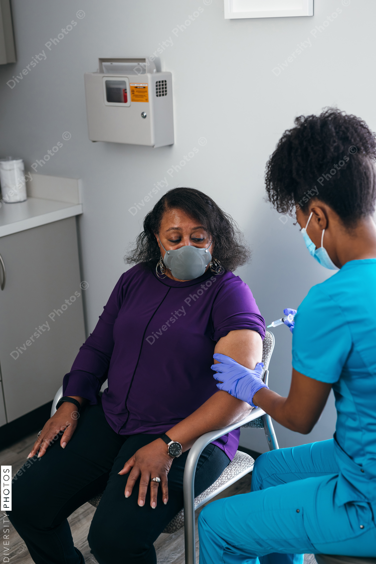 Black senior woman gets vaccine, from nurse at doctors office