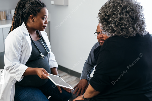 Black pregnant doctor explains lab results to senior patients using digital tablet 