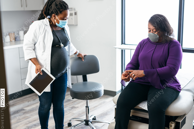 Pregnant doctor entering exam room to see senior woman patient