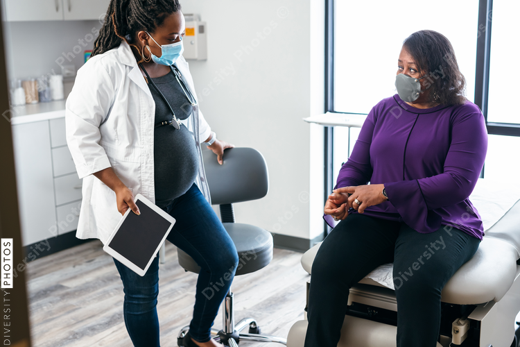 Pregnant doctor entering exam room to see senior woman patient