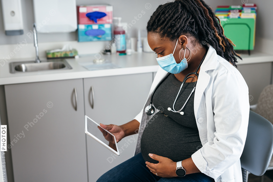 Black pregnant doctor reviewing medical records on tablet