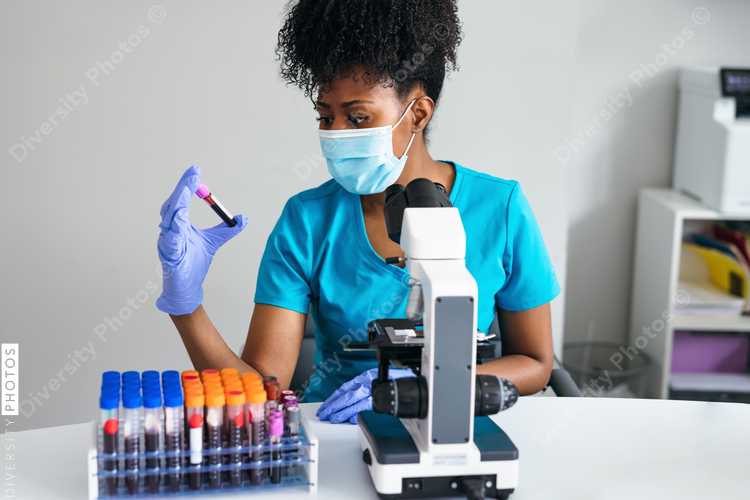 Black medical professional in a mask looks at blood sample label