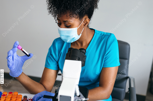 Black medical professional in a mask looks at blood sample label