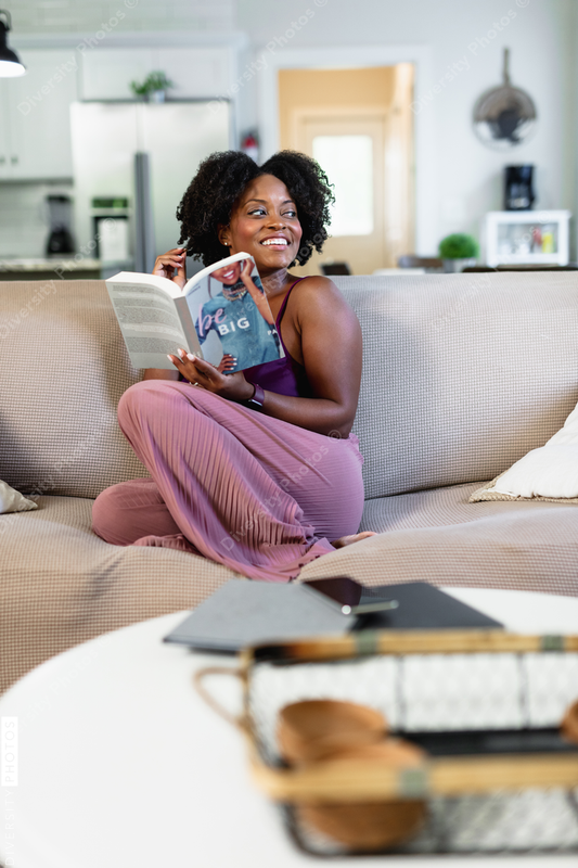 African American woman in pajamas reading book at home, comfort 