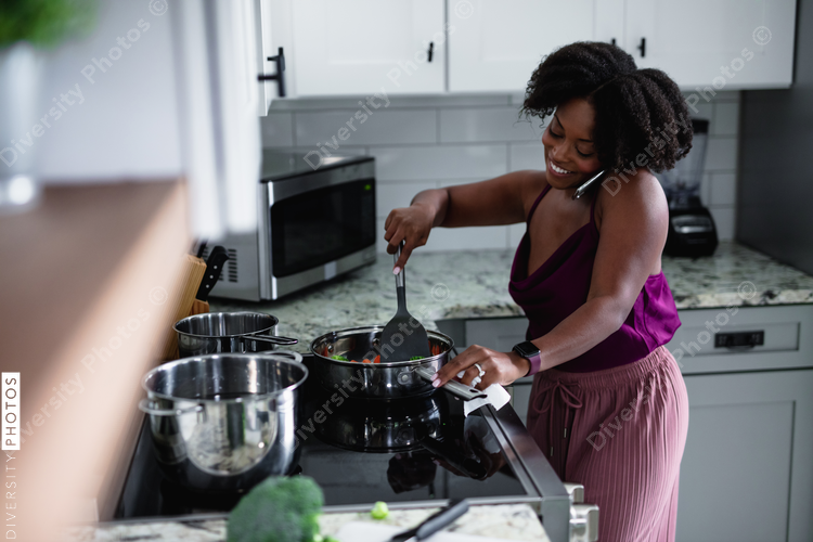 Black woman cooking at talking on phone, multitasking 