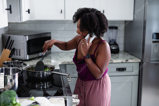 Black woman cooking at talking on phone, multitasking 
