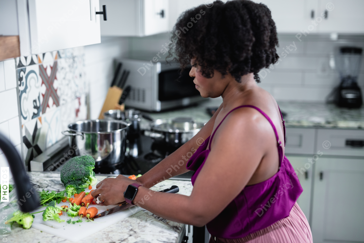 Woman dicing vegetables in kitchen, healthy