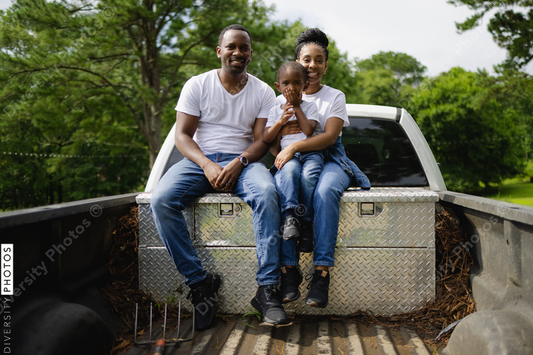 Portrait of parents with son sitting on pick up truck in rural environment, African American