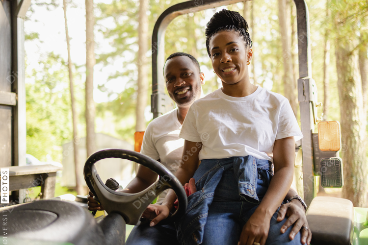 Smiling couple sitting on tractor in rural environment