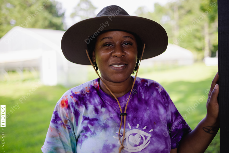 Portrait of female farmer standing in field in front of greenhouse at organic¬†farm