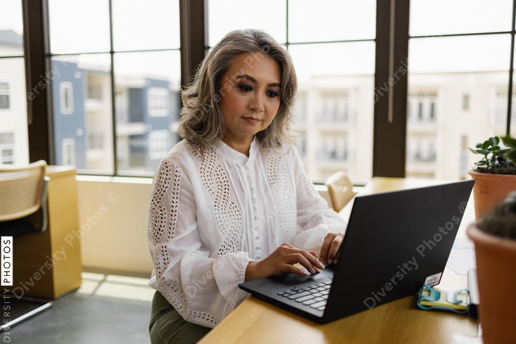 Businesswoman working on laptop in modern office, Chinese woman