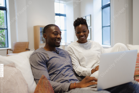 African American Smiling couple sitting on sofa and using laptop