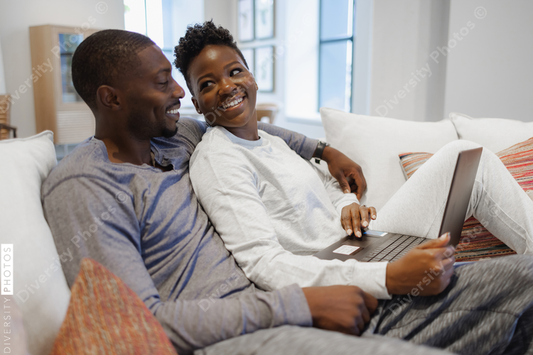 African American Smiling couple sitting on sofa and using laptop