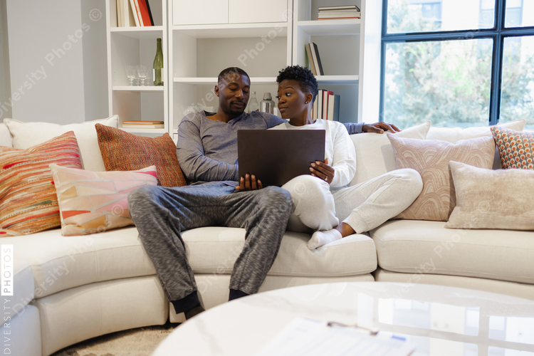 Couple sitting on sofa and using laptop