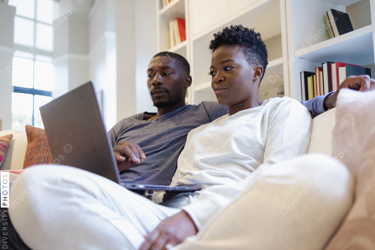 Couple sitting on sofa and using laptop