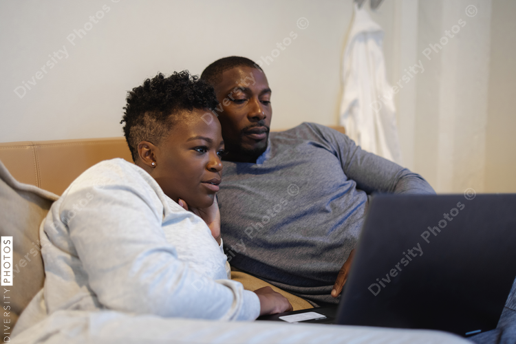 Couple lying in bed and using laptop