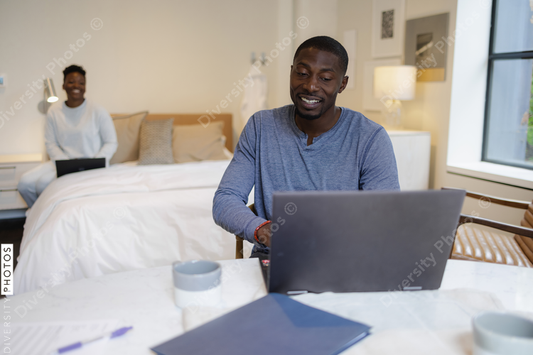 Black Couple using laptops in bedroom