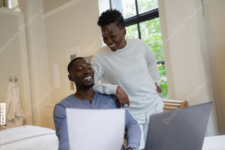 Smiling couple holding document and using laptop