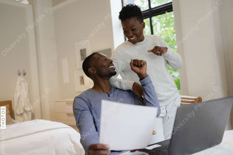 Smiling African American couple holding document and fist bumping