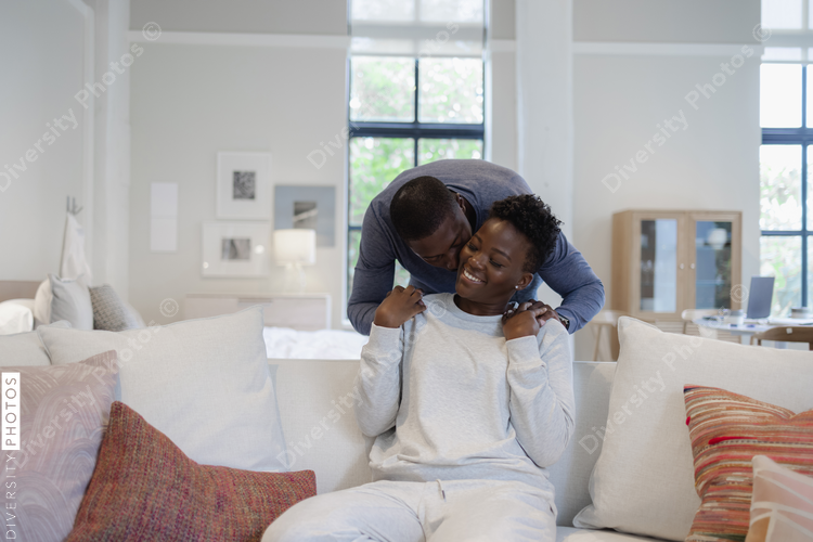 Black Couple holding hands and kissing on sofa