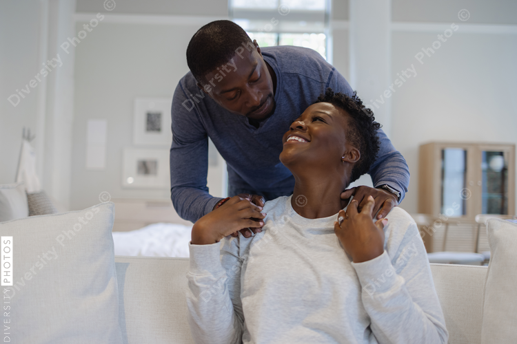 Smiling Black couple holding hands on sofa