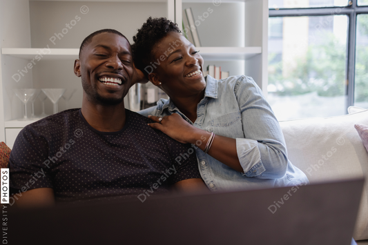 Black Couple sitting on sofa and laughing