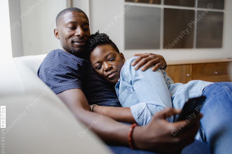 Couple lying on sofa and using smart phone