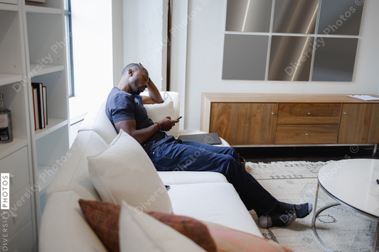 Black Man sitting on sofa and using smart phone