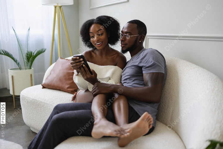Couple sitting on sofa and using smart phone