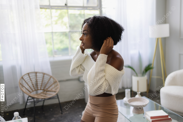 Young woman fixing hair in living room