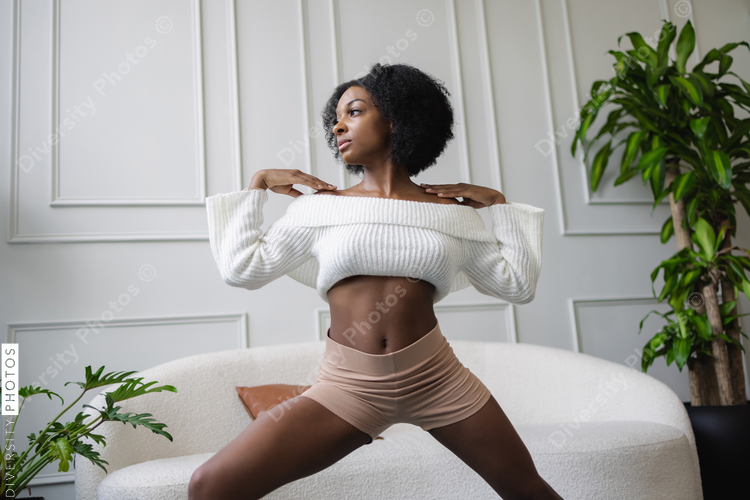 Young woman doing virabhadrasana yoga pose in living room